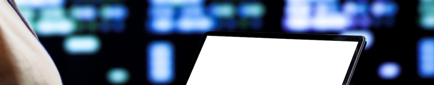 A man holding a laptop in a computer or server room.